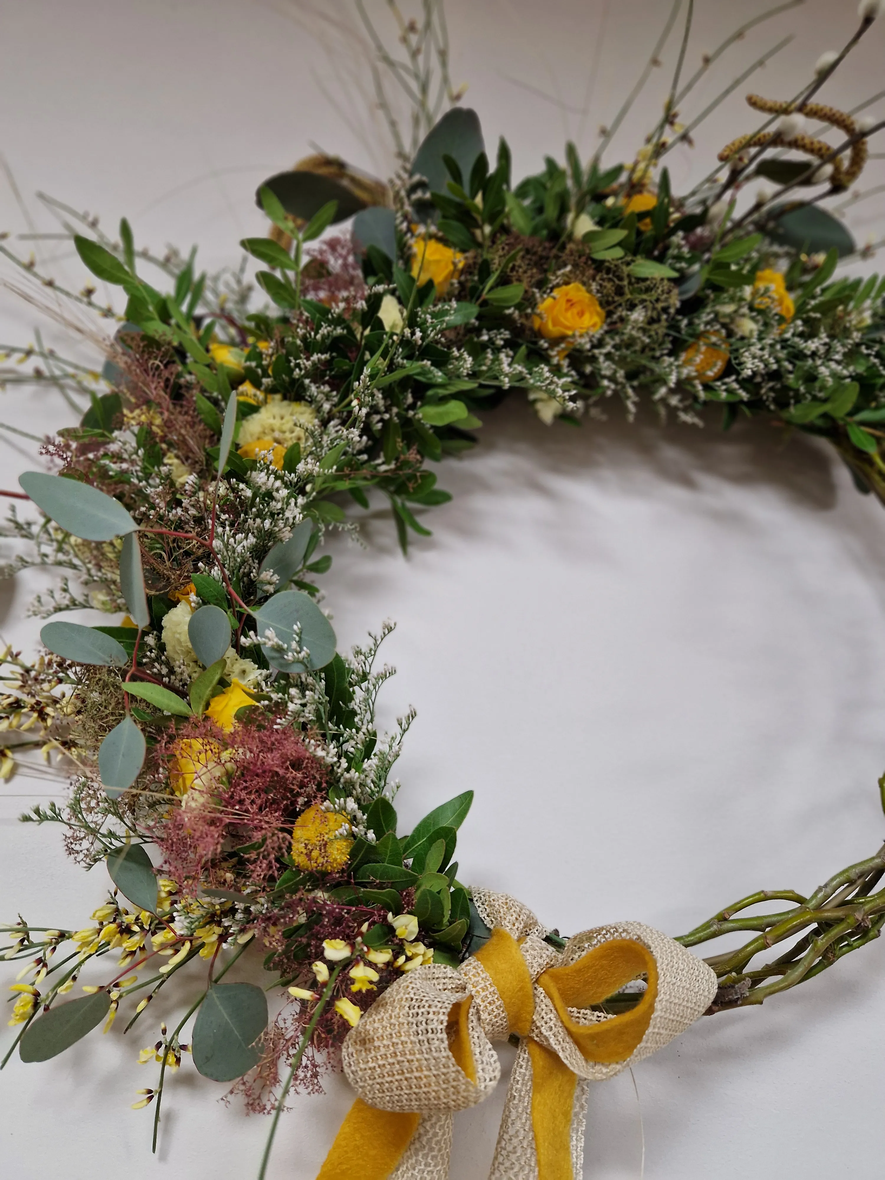 Blumenkranz mit gelben Blumen und Banddekoration.