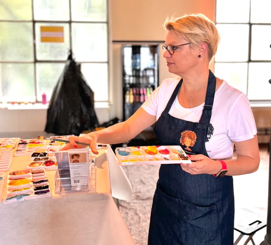 Frau hält Farbpalette im Kunststudio.