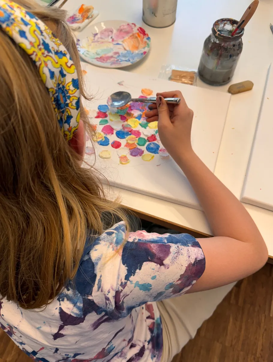 Child painting colorful circles with spoon technique.