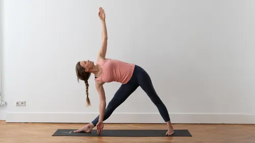 Woman practicing yoga pose on mat indoors.
