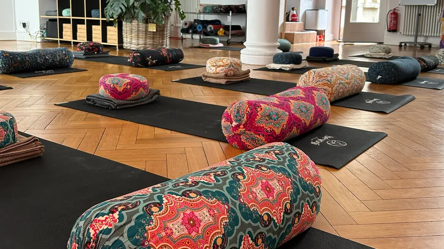 Vibrant yoga bolsters on mats in studio.