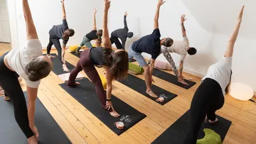 Gruppe übt Yoga auf Matten im Studio.