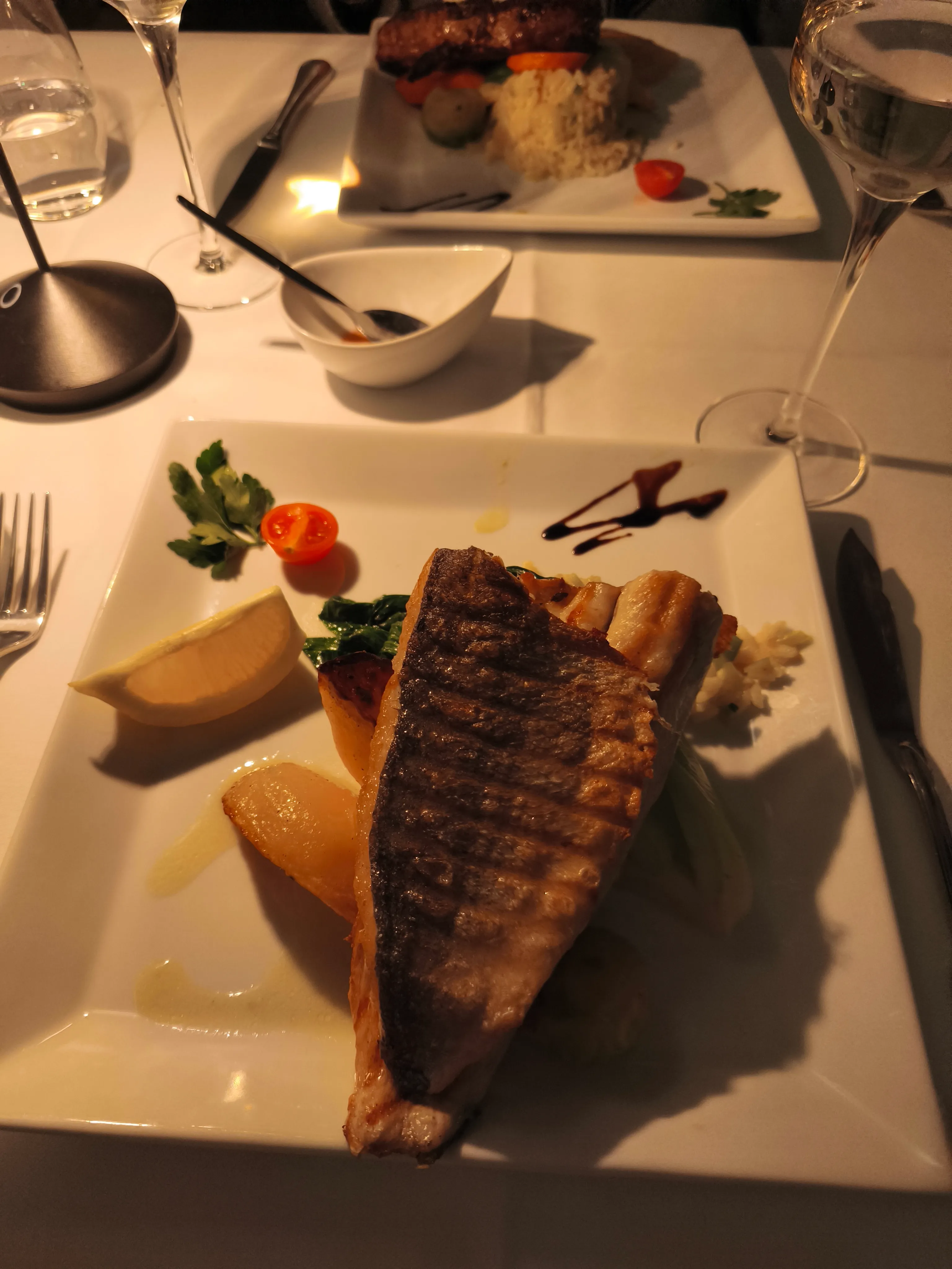 Gegrillter Fisch mit Beilage auf einem Teller.