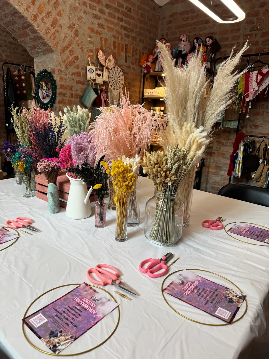 Basteltisch mit Trockenblumen und Scheren.