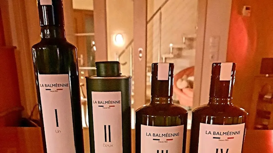 Four olive oil bottles on a wooden table.