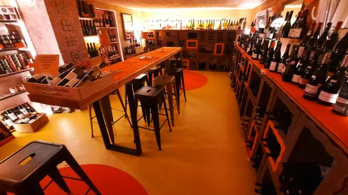 Wine cellar with bottles on shelves and tables.
