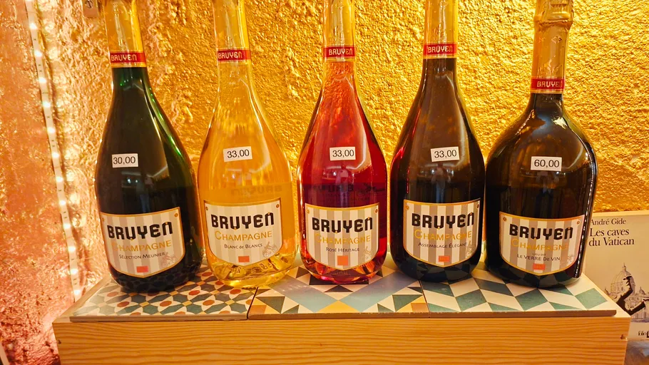 Five Bruyere champagne bottles on a decorative shelf.