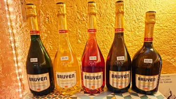 Five Bruyer champagne bottles against gold wall.