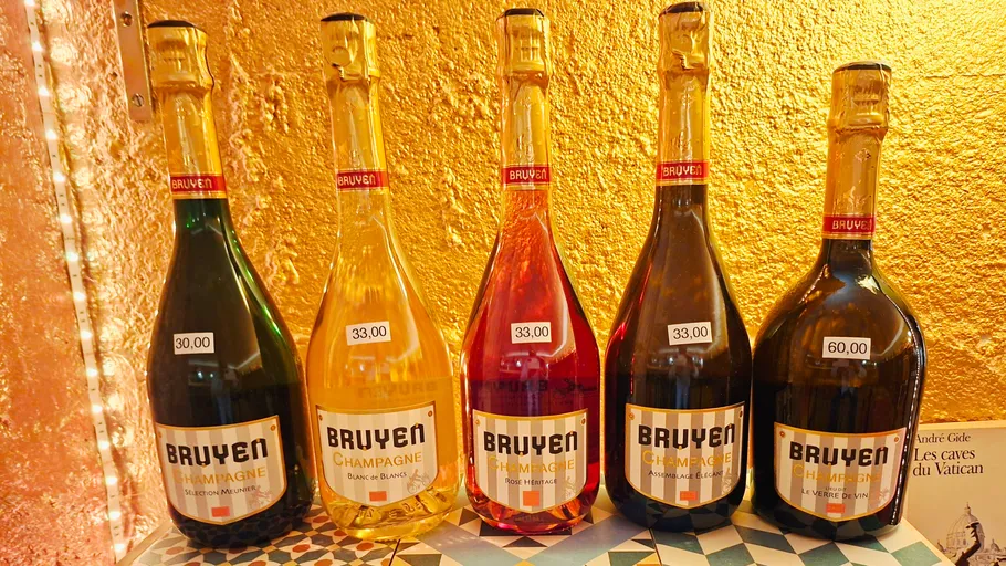 Fünf Bruyer Champagnerflaschen vor goldener Wand.
