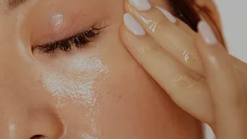 Nahaufnahme eines glänzenden Gesichts mit Hand.
