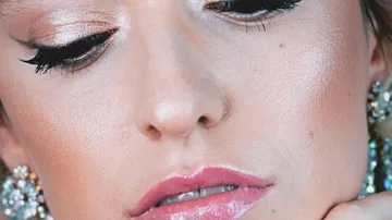 Nahaufnahme eines Frauengesichts mit Make-up und Ohrringen.