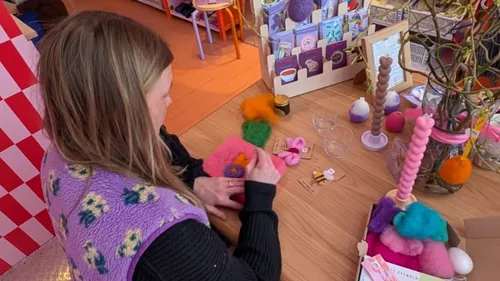 Person crafting with wool at a wooden table.