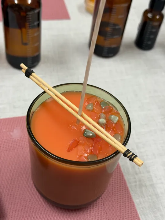 Glaskerze mit Docht sitzt auf Tisch.