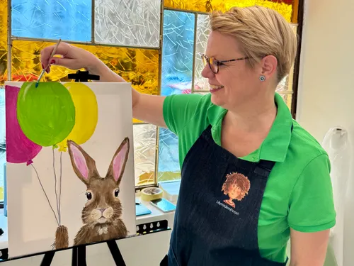 Person painting balloons and rabbit indoors.