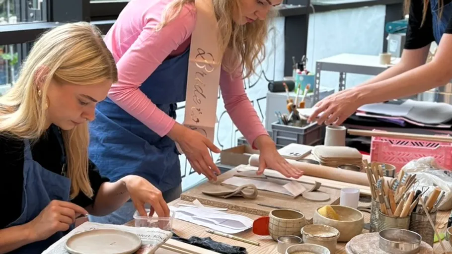 Two women crafting pottery indoors at a table.