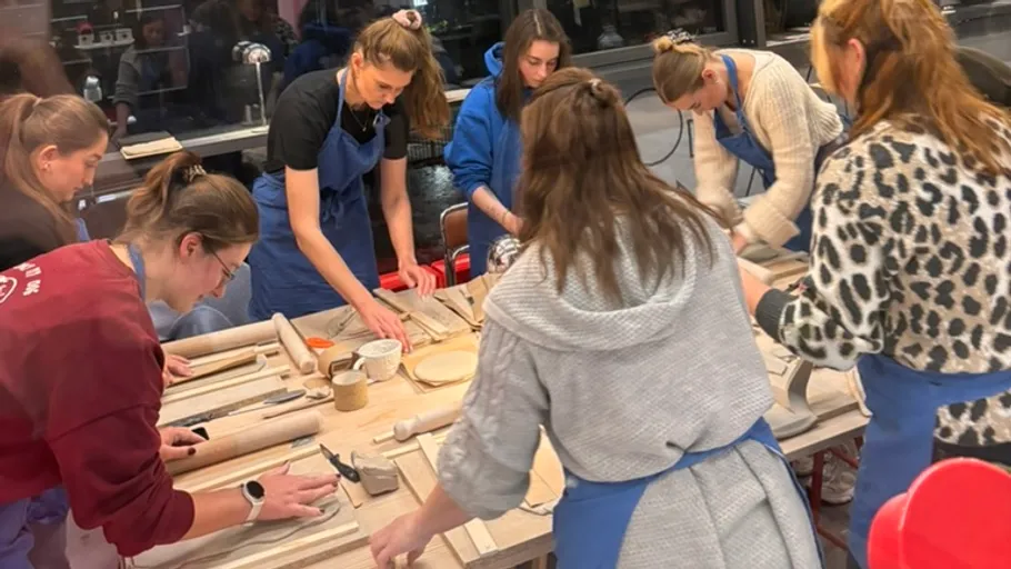 People crafting with clay at a table indoors.