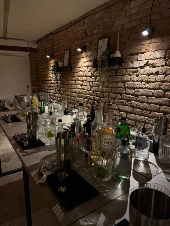 Cocktail-Setup auf Tischen vor Backsteinwand.