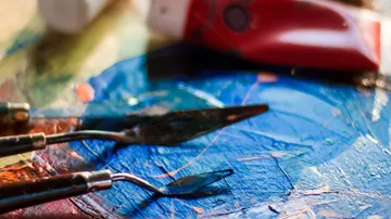 Paint spatulas on colorful abstract canvas.