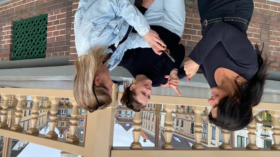 Three people chatting outdoors near a railing.