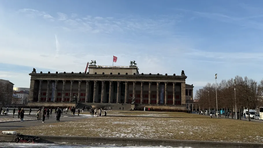 Large neoclassical building with columns; people walking outside.
