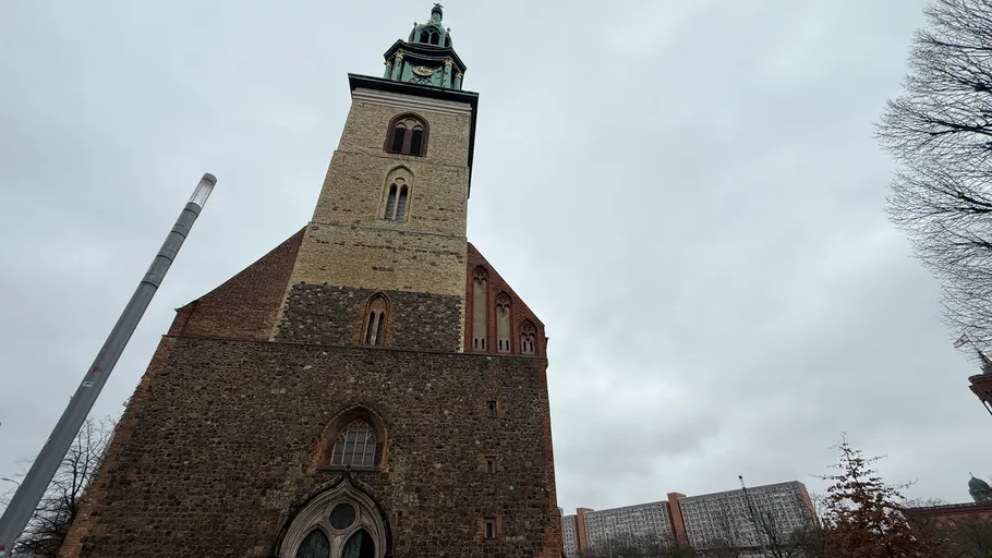 Historischer Kirchturm unter bewölktem Himmel.