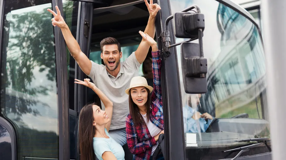 Gruppe von Freunden posiert begeistert am Bus-Eingang.