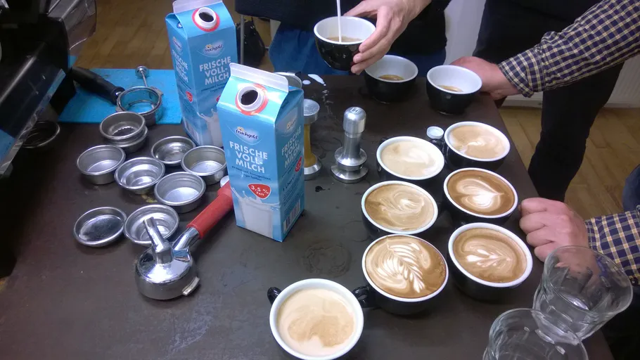 People making latte art in a coffee shop.