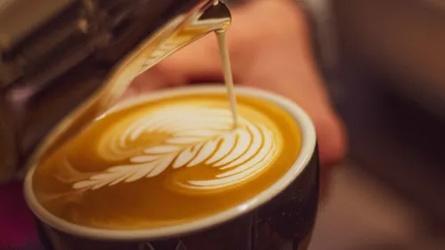 Milch wird in Kaffee für Latte-Art gegossen.
