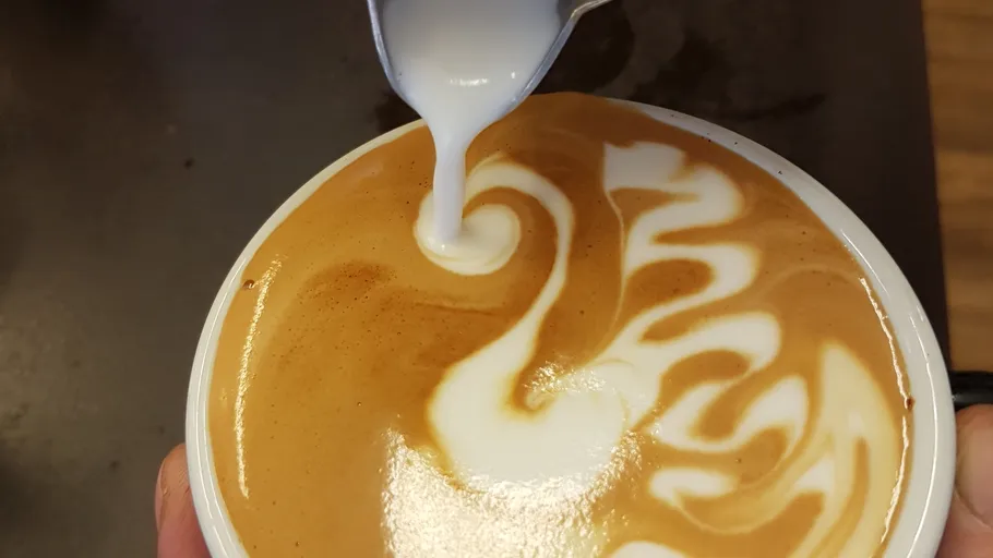 Latte art being created in a coffee cup.