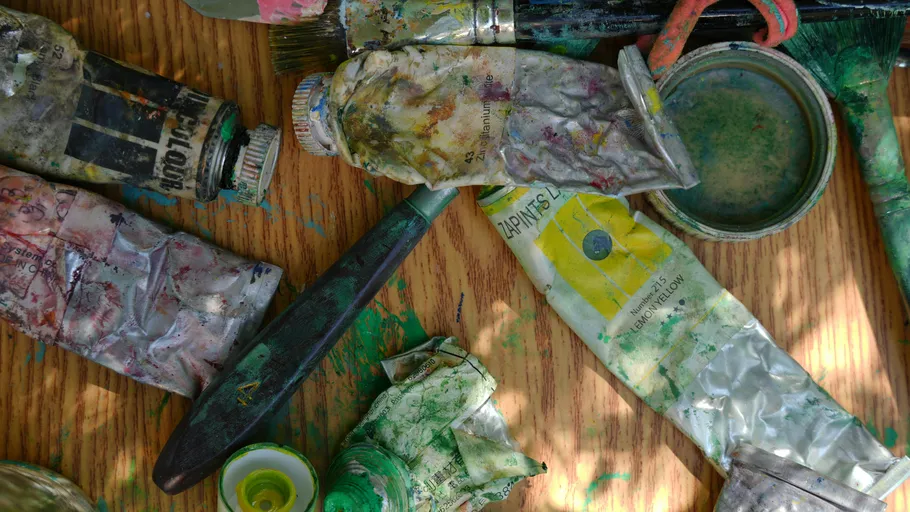 Used paint tubes and brushes on table.