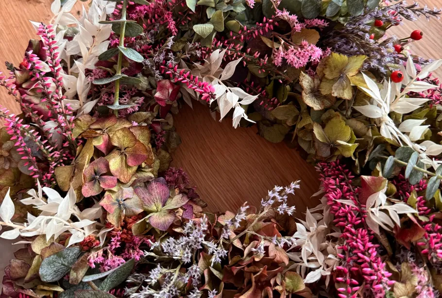 Bunter Kranz aus Trockenblumen auf Holztisch.