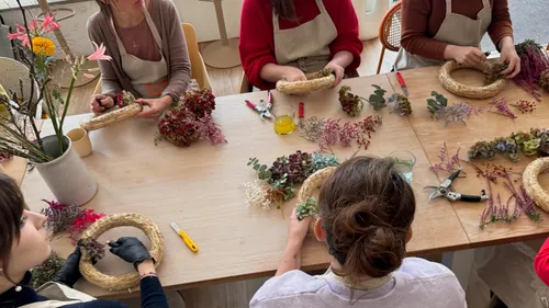 People crafting wreaths with dried flowers indoors.