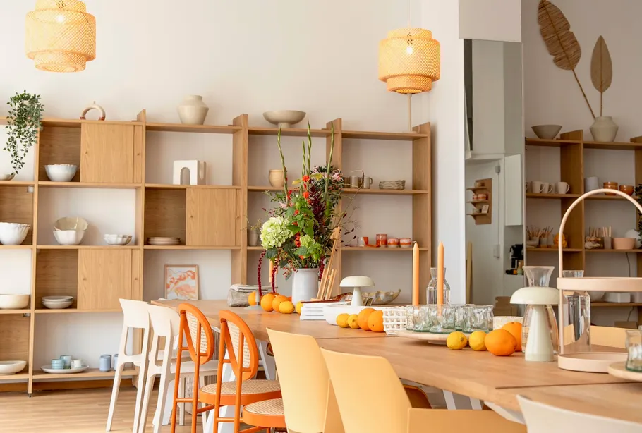Dining table with fruit and shelves in background.