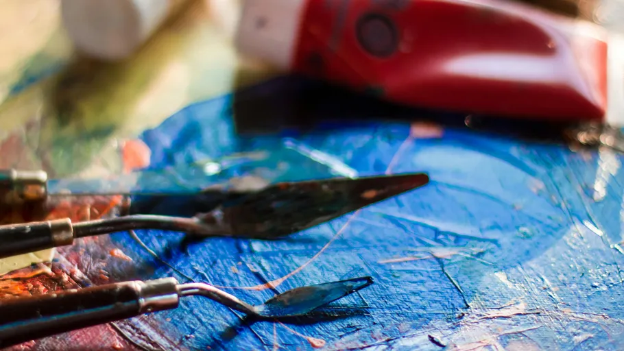 Palette knives on a colorful painted canvas.