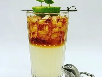 Ein Glas mit zwei Schichten Getränk und Limetten.