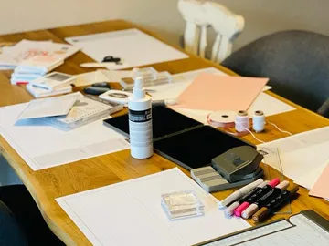 Papier, Stifte und Zubehör liegen auf einem Tisch verstreut.