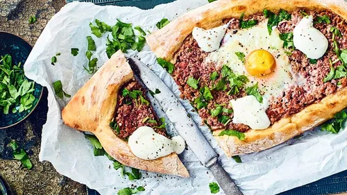 Brotboot mit Fleisch, Ei, Kräutern auf Papier.