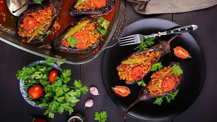 Gefüllte Auberginen mit Tomaten und Kräutern auf Tisch.