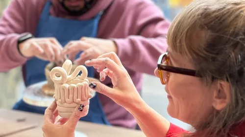 Two people crafting clay sculptures indoors.