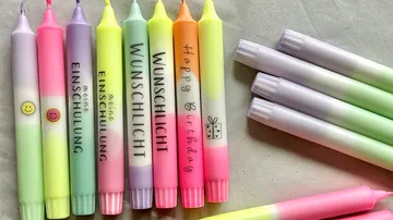 Bunte Kerzen mit Beschriftungen auf einem Tisch.