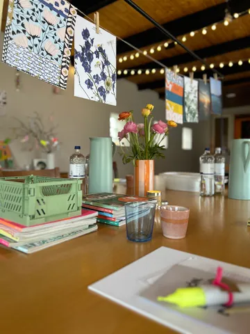 Tisch mit Blumen, Büchern und hängender Kunst.