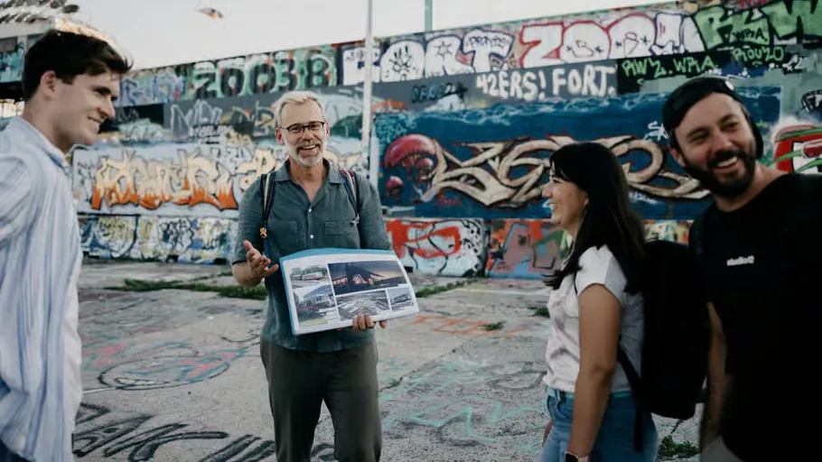 Group discussing in front of graffiti-covered wall.