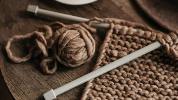 Stricknadeln und Garn auf Holztisch.