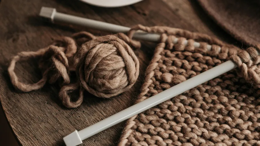 Knitting needles and yarn on wooden table.