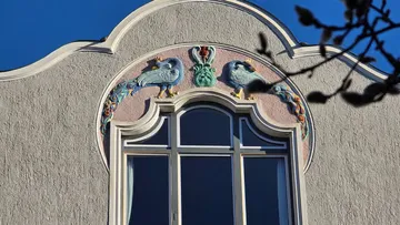 Art Nouveau facade with bird reliefs and window.