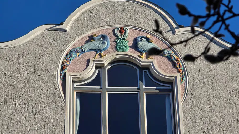 Art Nouveau facade with bird reliefs and window.