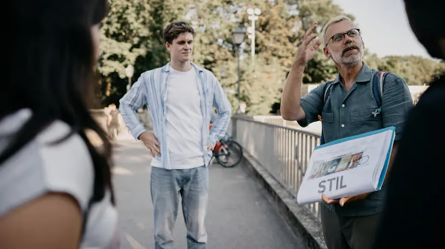 Man with folder talks to group outdoors.