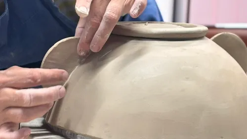 Hands molding clay on pottery wheel.