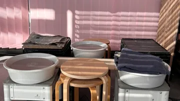 Two basins with water on boxes, surrounded by chairs.