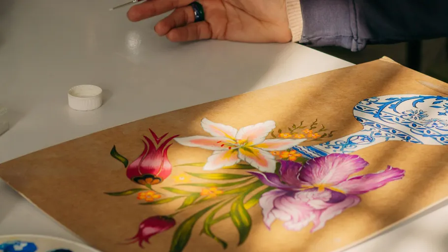 Person painting floral design on paper.